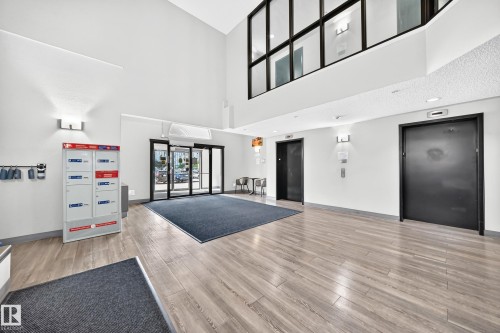 Spacious lobby with wood-finish flooring, high ceilings, and an upper-level interior window - #1303 330 Clareview Station Dr Nw, Edmonton, AB 