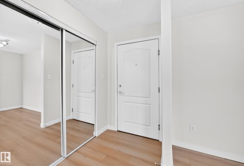 Wood-finish flooring throughout, white interior doors, mirrored closet doors, and white baseboards - #1303 330 Clareview Station Dr Nw, Edmonton, AB 