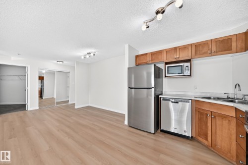 Kitchen featuring stainless steel appliances, wood cabinetry, and a double basin sink - #1303 330 Clareview Station Dr Nw, Edmonton, AB 
