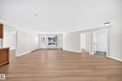Light-toned wood-finish flooring, white painted walls, and a white entry door with glass panels - 