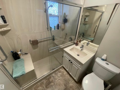 Glass-enclosed shower with a built-in bench and grab bar - 11230 96 Street Nw, Edmonton, AB 