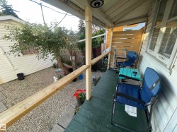 Covered porch with wood flooring and horizontal wood privacy screening - 