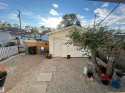 Gravel-covered yard with a detached storage shed, stepping stone pathway, and wood privacy fencing - 