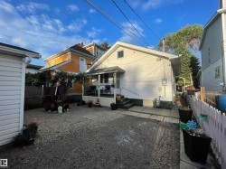 Gravel yard with a concrete pathway leading to a covered back entrance - 