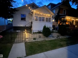 Enclosed front yard with a wrought iron fence, mature landscaping, and a concrete walkway - 