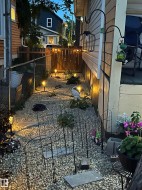 Gravel pathway with stepping stones, bordered by a wooden privacy fence and chain link fencing - 