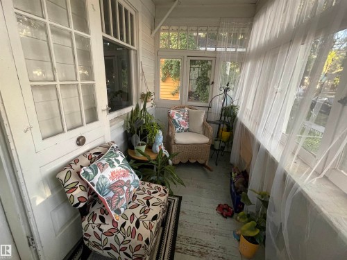 Enclosed porch with multiple windows, paneled walls, and a wood floor - 11230 96 Street Nw, Edmonton, AB 