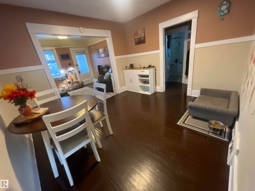 Dark-tone wood-finish flooring, two-tone painted walls with white trim, and white painted door frames create a cohesive interior - 11230 96 Street Nw, Edmonton, AB 