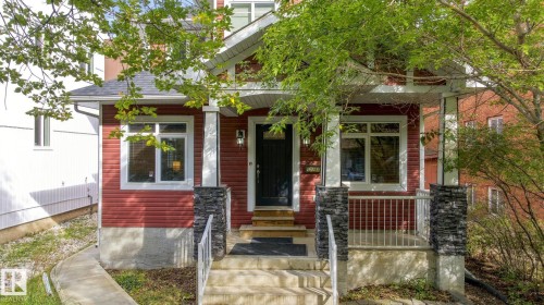 Red siding exterior with white trim, stone-clad porch columns, a covered entry, and a concrete walkway - 10143 123 Street Nw, Edmonton, AB 
