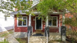 Red siding exterior with white trim, stone-clad porch columns, a covered entry, and a concrete walkway - 