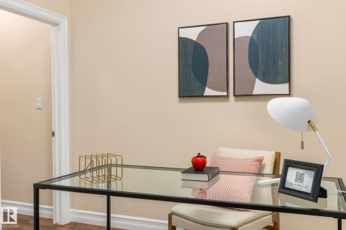 Glass-top desk with a metal frame, wood-finish flooring, and light-toned wall paint - 10143 123 Street Nw, Edmonton, AB 