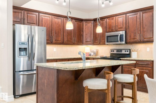 Kitchen featuring rich wood cabinetry, stainless steel appliances, a center island with a sink, granite countertops, and recessed lighting - 10143 123 Street Nw, Edmonton, AB 