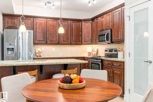 Kitchen featuring rich wood cabinetry, stainless steel appliances, light-toned countertops, and track lighting - 10143 123 Street Nw, Edmonton, AB 