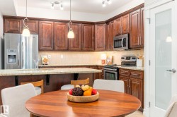 Kitchen featuring rich wood cabinetry, stainless steel appliances, light-toned countertops, and track lighting - 