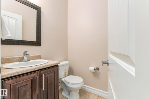 Vanity with wood-finish cabinetry, countertop with integrated sink, and an ornamental framed mirror - 10143 123 Street Nw, Edmonton, AB 