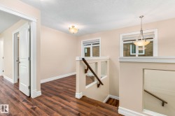 Wood-finish flooring throughout, white trim, recessed staircase with wood handrail, and contemporary pendant lighting - 