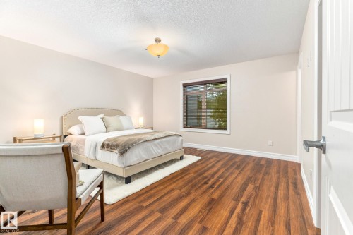 Expansive room with wood-finish flooring, neutral wall tones, and a window with blinds - 10143 123 Street Nw, Edmonton, AB 
