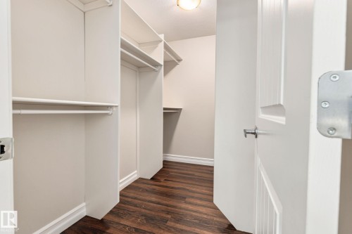 Built-in closet shelving, integrated hanging rods, wood-finish flooring, white trim, and a panel door with a satin nickel handle - 10143 123 Street Nw, Edmonton, AB 