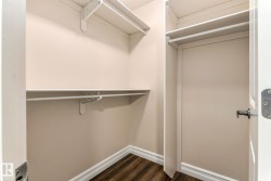 Walk-in closet with multi-level shelving, hanging rods, and wood-finish flooring - 