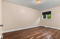 Wood-finish flooring, neutral wall paint, white trim, single window with black blinds, and a flush-mount ceiling light - 