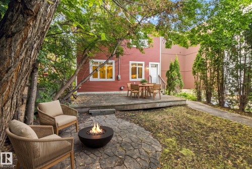 Backyard space featuring a stone patio, wooden deck, and mature trees - 10143 123 Street Nw, Edmonton, AB 