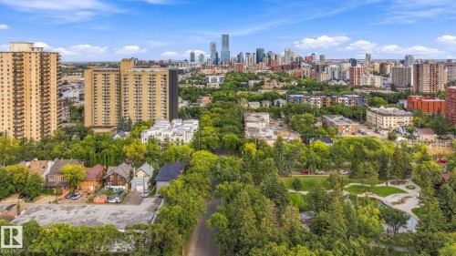 Lush tree-lined streetscape with a city skyline backdrop, featuring a mix of residential buildings and green spaces - 10143 123 Street Nw, Edmonton, AB 