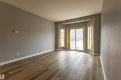 Spacious room featuring wood-finish flooring, light grey walls, and white baseboards - 