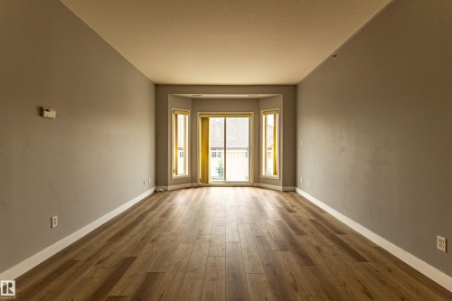 Room featuring wood-finish flooring, neutral wall tones, and white baseboards - #412 4304 139 Av Nw, Edmonton, AB - Indoor Photo Showing Other Room