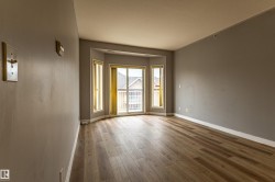 Spacious room featuring wood-finish flooring, light gray walls, and white baseboards - 