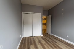 Room featuring wood-finish flooring, light grey walls, white baseboards, and a bi-fold closet door - 