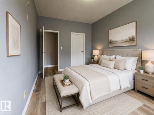 Bedroom featuring light wood-finish flooring, two white panel doors, and neutral gray wall tones - #412 4304 139 Av Nw, Edmonton, AB - Indoor Photo Showing Bedroom