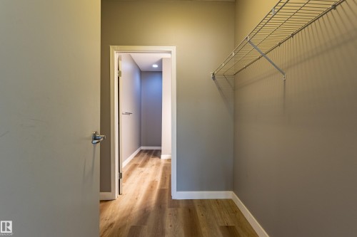 Interior hallway featuring wood-finish flooring, light gray wall paint, white baseboards, and a recessed ceiling light - #412 4304 139 Av Nw, Edmonton, AB - Indoor