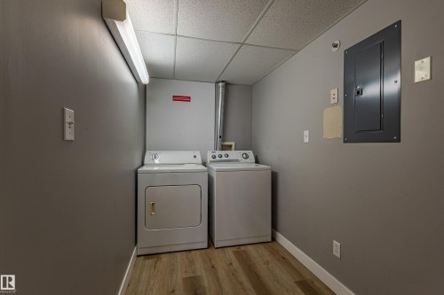 Laundry area featuring wood-finish flooring, drop ceiling, and neutral wall paint - #412 4304 139 Av Nw, Edmonton, AB - Indoor Photo Showing Laundry Room
