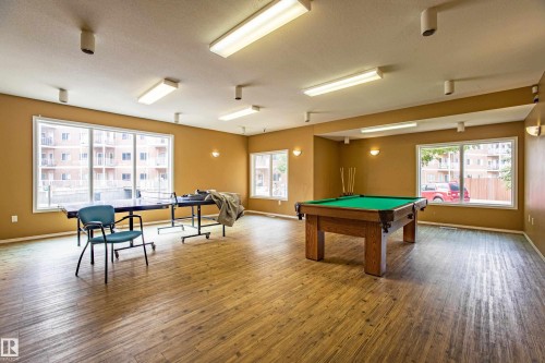 Spacious recreation room featuring wood-finish flooring and multiple windows - #412 4304 139 Av Nw, Edmonton, AB - Indoor Photo Showing Other Room