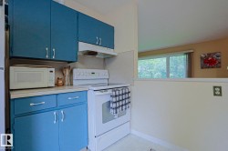 Kitchen featuring blue cabinetry, white countertops, built-in range, and a window - 
