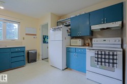 Kitchen featuring painted cabinetry, white appliances, and a window providing natural light - 