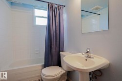 White tile shower surround with a built-in soap dish, pedestal sink with chrome faucet, and wall-mounted mirror - 