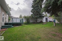 Rear yard featuring a raised deck with railing, a storage shed, and mature trees - 