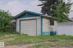 Detached garage with a paneled door, a side window, and an exterior finished in stucco - 