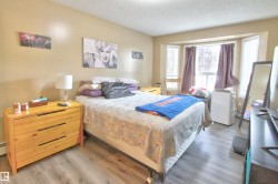 Bedroom featuring wood-finish flooring, a bay window with multiple panes, and neutral wall tones - 