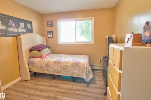 Bedroom featuring wood-finish flooring, a window with blinds, and neutral wall tones - #106 2 Alpine Bv, St. Albert, AB - Indoor Photo Showing Bedroom