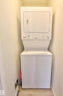 Stackable white laundry appliances with wood-finish flooring - 