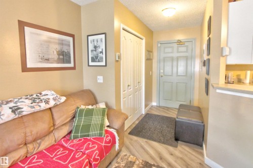 Entryway featuring wood-finish flooring, a bi-fold closet door, and a light-colored entry door - #106 2 Alpine Bv, St. Albert, AB - Indoor Photo Showing Other Room