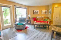 Spacious living area featuring wood-finish flooring, a large window, and a full-light exterior door - 