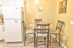 Kitchen area featuring white cabinetry, a built-in refrigerator, and wood-finish flooring - 