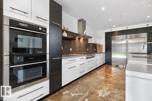 Modern kitchen featuring stainless steel double ovens, a large built-in refrigerator, and a gas range with a stainless steel vent hood - 14A Birch Drive, St. Albert, AB 