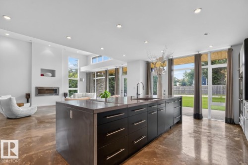 Open-concept kitchen and living area featuring a large center island with integrated sink, recessed lighting, and expansive glass doors - 14A Birch Drive, St. Albert, AB 
