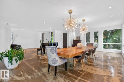 Open concept living area with polished concrete flooring, recessed lighting, expansive windows, and two ornate chandeliers - 14A Birch Drive, St. Albert, AB 