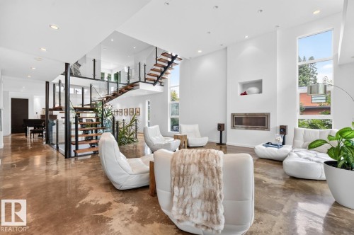 Polished concrete flooring, multi-level floating staircase with glass railings, built-in fireplace, and high ceilings with recessed lighting - 14A Birch Drive, St. Albert, AB 