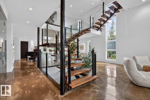 Floating staircase with glass panel railing and wood treads, polished concrete flooring, recessed lighting, and expansive windows - 14A Birch Drive, St. Albert, AB 